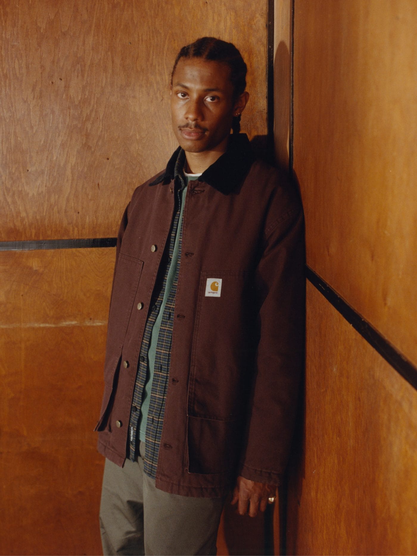 Homme portant une veste en toile bordeaux Carhartt WIP à col en velours côtelé sur une chemise à carreaux