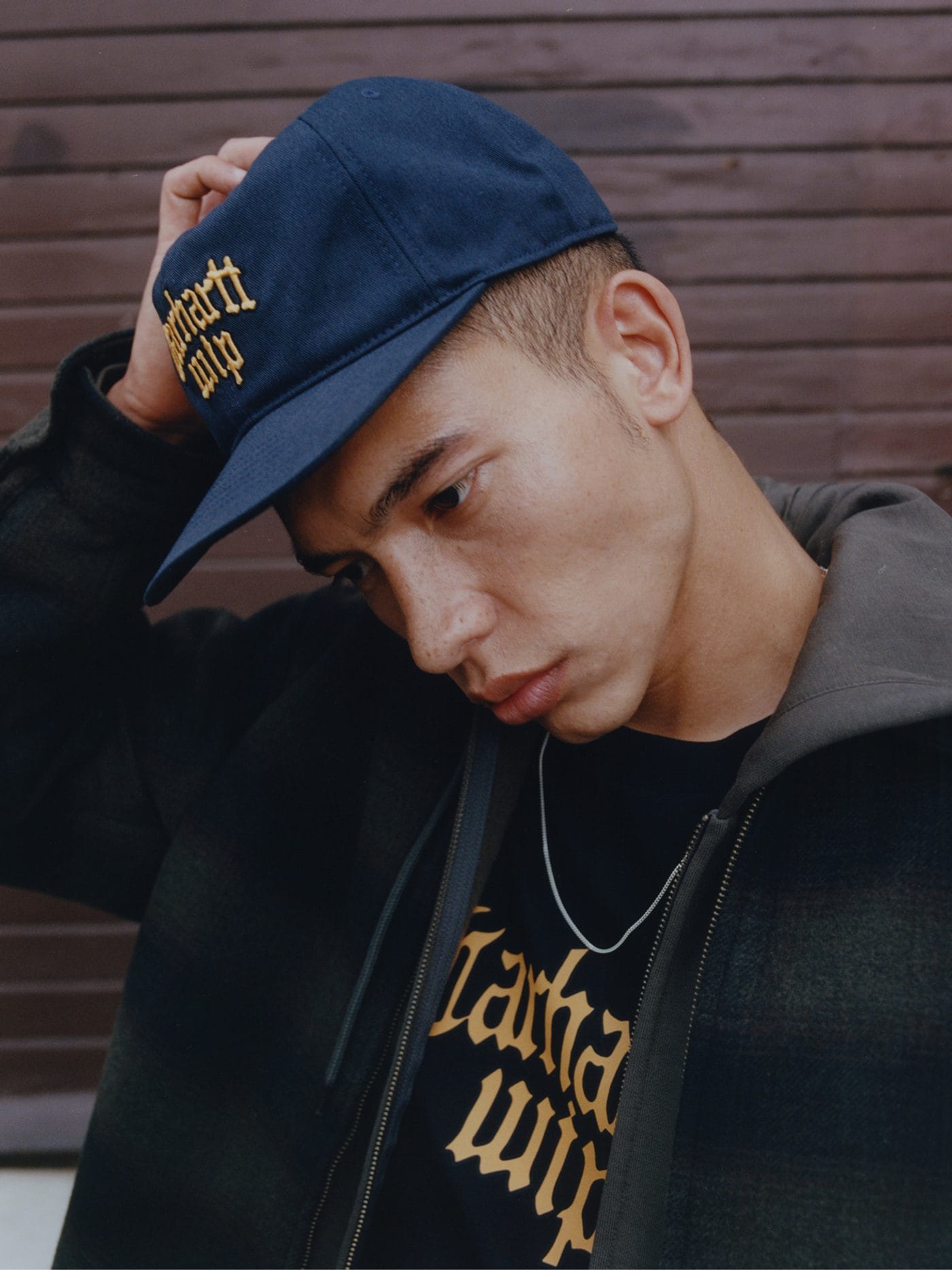 Gros plan sur une casquette bleu marine et un tee-shirt noir portant le logo Carhartt WIP en jaune